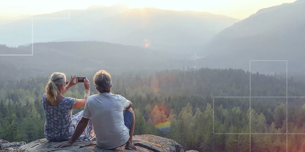 A couple capturing mountains at sunset under a golden sky