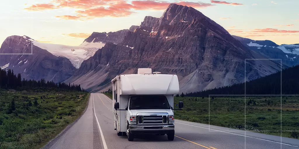 Un camping-car sur une route de montagne durant le coucher de soleil.